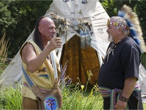 Gilles Wanlinas Dorais (left) of the Abenaki First Nations and Archie Martin of the Mi'kmaq First Nations talk on Skype with a friend in Mexico with a mobile phone during the Hudson Street Fair in 2014, when they had set up an information stall with displays and information about First Nations cultures.