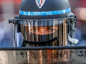 A police officer looks on from behind a riot shield during an anti-government demonstration called by the "yellow vests" movement in Paris on Saturday, April 20, 2019.