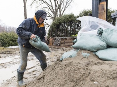 Claude Hamelin places a sandbag next to the foundation of his home in Rigaud, Que., Friday, April 19 2019.