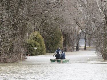 People are pulled in a small boat along a residential street surrounded by floodwaters in Rigaud, on Saturday, April 20, 2019.