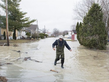 William Bradley wades through floodwaters on a residential street next to his home in Rigaud, on Saturday, April 20, 2019.