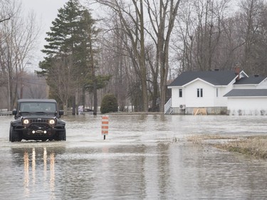 A jeep makes its way along a flooded road in the town of Rigaud, Que, west of Montreal, Sunday, April 21, 2019.
