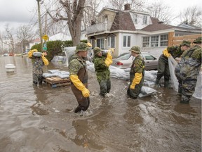 Canadian Forces personnel sandbag a house against the floodwaters Thursday in Laval.