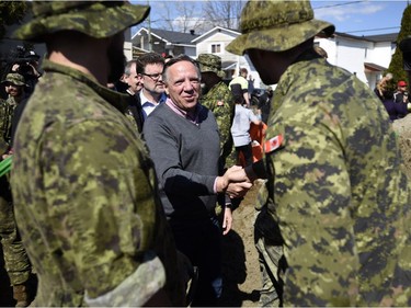 Quebec Premier Francois Legault speaks to Canadian Forces members filling sandbags as he visits a flooded area on Rue Saint-Louis in Gatineau, Que., on Monday, April 22, 2019.