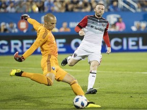 DC United's Wayne Rooney, right, seen in a game from last year pressuring Impact goalkeeper Evan Bush, did not dress for Tuesday night's game. He was sitting out an automatic one-game suspension for receiving a red card in DC United's last match on Saturday.