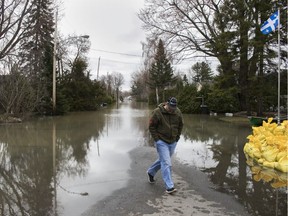 A man walks away from a flooded street in Ste-Marthe-sur-le-Lac near Montreal Sunday April 28, 2019 the day after Lac des Deux Montagnes breached a dike in the community. Several thousand people were forced from their homes suddenly last night with little more than the clothes on their backs.