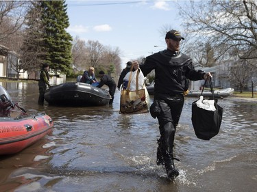 A member of the Navy carries bags from a resident they escorted to pick up possessions from her home on a flooded street in Sainte-Marthe-sur-le-Lac, Quebec April 30, 2019.