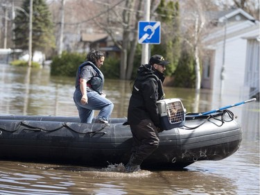 A member of the Navy carries a woman's cat after she was escorted to her home to pick up possessions on a flooded street in Sainte-Marthe-sur-le-Lac, Quebec April 30, 2019.