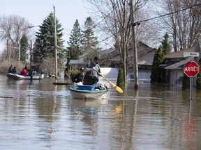 Residents use boats to pick up possessions on a flooded street in Ste-Marthe-sur-le-Lac on April 30, 2019.