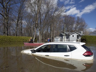 A canoe passes a submerged car on a flooded street in Sainte-Marthe-sur-le-Lac, Quebec April 30, 2019.