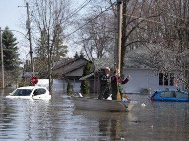 Residents take photos as they maneuver around a flooded car after picking up possessions from their home in Sainte-Marthe-sur-le-Lac, Quebec April 30, 2019.