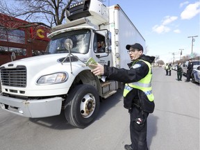 MONTREAL, QUE.: APRIL 30, 2019 -- A Montreal Police officer directs a truck to a staging area during an awareness campaign by Montreal Police and agents from Controle routier Québec to remind truck drivers of safe driving habits, in Montreal Tuesday April 30, 2019.  The majority of fatal pedestrian accidents are caused by heavy vehicles in urban areas.  (John Mahoney / MONTREAL GAZETTE) ORG XMIT: 62445 - 8418