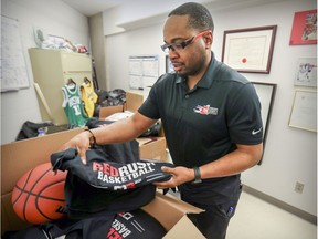 Denburk Reid, executive director of Montreal Community Cares, unboxes T-shirts in his office at Loyola High School.