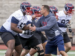 Montreal Alouettes assistant coach André Bolduc takes on offensive lineman Jarvis Harrison during first day of rookie camp at Molson Stadium on Wednesday.