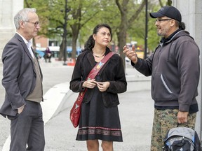 Nakuset, centre, executive director of the Native Women's Shelter of Montreal, speaks with Liberal MNA David Birnbaum, left, opposition critic for indigenous affairs, and community intervention worker David Crane in Cabot Square.