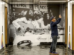 Marc Anthony Zamora takes a picture of John Lennon quotations posted on the walls between elevators with a Gerry Deiter photograph on the wall commemorating the 50th anniversary of the Lennon and Yoko Ono's bed-in at the Queen Elizabeth Hotel in Montreal Thursday May 23, 2019.