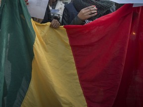 The Malian flag is held during a Montreal vigil to raise awareness for victims of overlooked terrorist attacks in 2016.