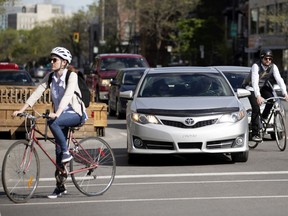 Two cyclists contend with traffic on on St-Denis St. on Monday.