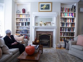 Mary Larson reads in her Westmount living room, which features floor-to-ceiling bookshelves.