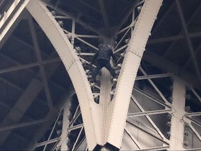 A climber is pictured between two iron columns of the Eiffel Tower Monday, May 20, 2019 in Paris. The Eiffel Tower has been closed to visitors after the man has tried to scale it. (AP Photo/Michel Euler)