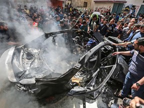 Palestinian emergency personnel try to put out the fire on a car belonging to Hamas member Hamad al-Khodori, in Gaza City on May 5, 2019, after it was hit by an Israeli airstrike. - A Palestinian militant was killed in an Israeli retaliatory strike in the Gaza Strip, Gazan officials said, in response to rocket barrages fired from the enclave.