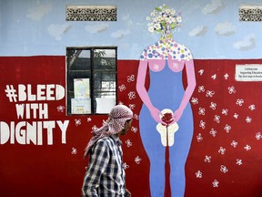 A man walks past a mural about menstruation at a school for underprivileged children, Parijat Academy, on the Menstrual Hygiene Day in Guwahati, India.