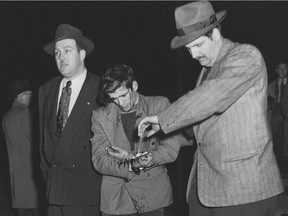 A bleeding striker is escorted by police out of church hall in Asbestos, Quebec following a dawn raid in May 1949.