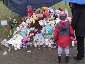 A woman and her son pay their respect in front of the house where lived a 7-year-old girl who was found in critical condition in her home on Monday in Granby, Que. on Friday, May 3, 2019. Two adults, identified by people close to the family as the girl's father and his partner, were both charged with unlawful confinement while the partner was also charged with aggravated assault.