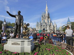 FILE - In this Jan. 9, 2019 photo, guests watch a show near a statue of Walt Disney and Micky Mouse in front of the Cinderella Castle at the Magic Kingdom at Walt Disney World in Lake Buena Vista, Fla. The Walt Disney Company reports financial results Wednesday, May 8. (AP Photo/John Raoux) ORG XMIT: NYBZ337
