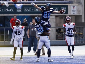 Toronto Argonauts' James Wilder Jr. (32) lifts up wide receiver Jimmy Ralph after a touchdown during preseason CFL game action against the Montreal Alouettes at Varsity Stadium in Toronto on Thursday, May 30, 2019.