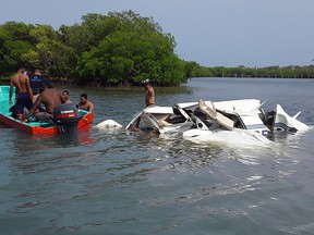 This handout picture shows Honduran firefighters at the site of an accident where a light plane crashed into the sea at the Isla Bonita Area, in Roatan, Honduras, on Saturday, May 18, 2019.