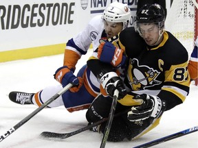 Sidney Crosby, right, of the Pittsbrgh Penguins is given a rough ride by Adam Pelech of the New York Islanders in Game 4 of first-round hockey series on April 16, 2019.