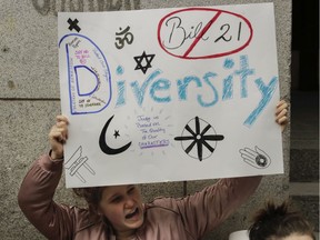 A woman holds up a sign while chanting during a protest against Bill 21 outside the Quebec immigration office on Notre Dame St. Friday, April 12, 2019 in Montreal. The protesters were mostly CEGEP and university students.