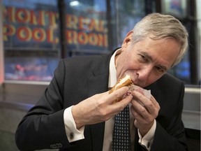 Montreal Pool Room owner Socrates Goulakos bites into the establishment's famous hot dog in 2019.