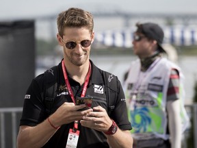 Haas driver Romain Grosjean of France smiles as he reads his phone in the paddock at Circuit Gilles-Villeneuve  in Montreal on Friday, June 7, 2019.