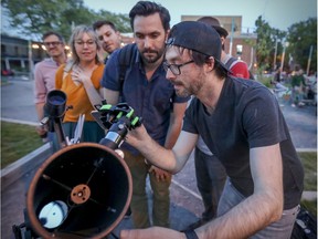 Trevor Kjorlien helps a moonstruck passerby take a picture of the moon via the telescope he sets up most clear nights at the corner of Mont-Royal and Boyer. (John Mahoney / MONTREAL GAZETTE)