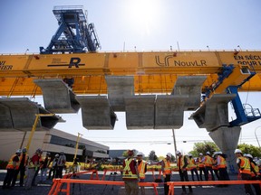 Work crews lift one of several prefab sections that will make up a REM rail bridge during a media tour of the REM construction project in Montreal on Tuesday, June 18, 2019.
