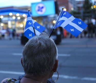 A woman watches the Fête Nationale parade on St. Denis St. in Montreal on Monday, June 24, 2019.