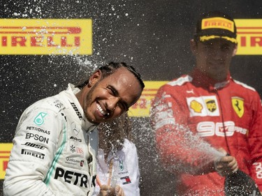 MONTREAL, QUE.: June 9, 2019 -- Mercedes AMG Petronas Motorsport driver Lewis Hamilton (44) of Great Britain basks in a faint spray of champagne from Scuderia Ferrari Mission Winnow driver Charles Leclerc (16) of Monaco during the Canadian Grand Prix at the Circuit Gilles Villeneuve in Montreal, on Sunday, June 9, 2019. Hamilton was handed the Winn after race officials penalized Vettel with a 5 second penalty.