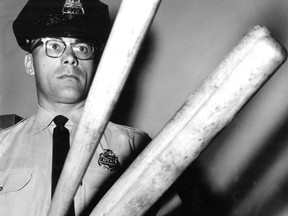 Montreal police Const. Jean-Louis Lavallee holds three baseball bats allegedly found in the car of three suspected arrested for "election irregularities" as federal elections were held on June 18, 1962. This photo was published in the Montreal Gazette the following day.