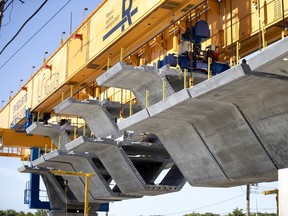 One of two custom built cranes lifts prefabricated concrete sections in to place for the REM rail line.