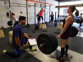 CrossFit coach Kory Cook (L) watches Erin Lindheim (R) do a deadlift during a CrossFit workout at Ross Valley CrossFit on March 14, 2014 in San Anselmo, California. CrossFit, a high intensity workout regimen that is a constantly varied mix of aerobic exercise, gymnastics and Olympic weight lifting, is one of the fastest growing fitness programs in the world.
