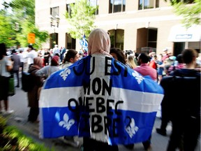 A woman holds a flag with the slogan "Where is my free Quebec" while protesting Quebec's new Bill 21, which will ban teachers, police, government lawyers and others in positions of authority from wearing religious symbols such as Muslim head coverings and Sikh turbans, in Montreal, Quebec, Canada, June 17, 2019.  REUTERS/Christinne Muschi