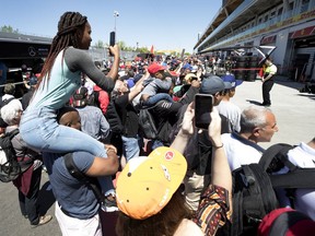 A woman gets a boost to take a picture of Mercedes AMG Petronas Motorsport driver Lewis Hamilton (44) of Great Britain during the annual Grand Prix open house at Circuit Gilles Villeneuve  in Montreal on Thursday, June 6, 2019.