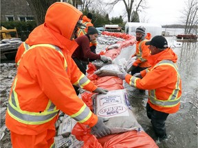 Municipal workers reinforce a dike at the end of Legault St. in the Pierrefonds-Roboro borough of Montreal on Wednesday, April 24, 2019.