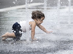 One-year-old Sasha Hadad, visiting Montreal with his parents from Brazil, plays in one of the fountains at Place des Festivals in Montreal July 3, 2019. Such moves to beat the heat can be a good idea, as infants and toddlers are particularly vulnerable to dehydration or heat exhaustion.