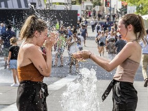 Laurie Breton, right, splashes her friend Alyson Paradis while cooling off in one of the fountains at Place des Festivals in Montreal Wednesday July 3, 2019. (John Mahoney / MONTREAL GAZETTE)