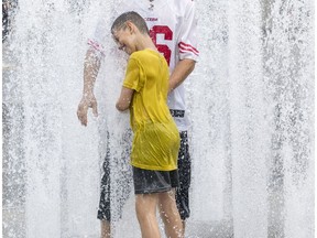 Gaël Daoust and his son Theo cool off in one of the fountains at Place des Festivals in Montreal Wednesday July 3, 2019.