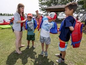 Lachine Racing Canoe Club manager Alexie Gomez helps Christophe Masella, Jacob Klevinas and Édouard Brault with their life-jackets on Tuesday July 9, 2019.