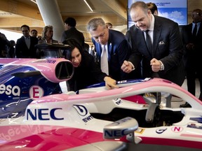 Benoît Dorais, right, checks out one of Lance Stroll's cars on display in the new F1 garage and paddock area of Circuit Gilles Villenuve on May 15, 2019.  Montreal Mayor Valérie Plante is see. at left, with François Dumontier in the middle.